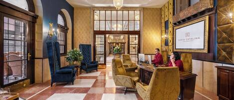 A lobby with a checkered floor, a reception desk, and two receptionists.