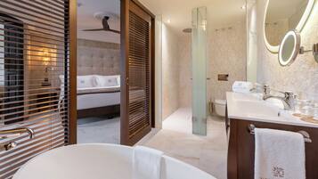 A modern bathroom with a bathtub, a large mirror, and a vanity with a towel hanging on the door.