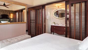 A hotel room with a large bed, a vanity with a mirror, and a ceiling fan.
