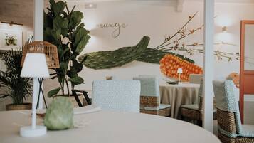 Un espacio interior acogedor con mobiliario de mimbre, una decoración de cactus y una pared con un letrero que dice 'muxgo'.
