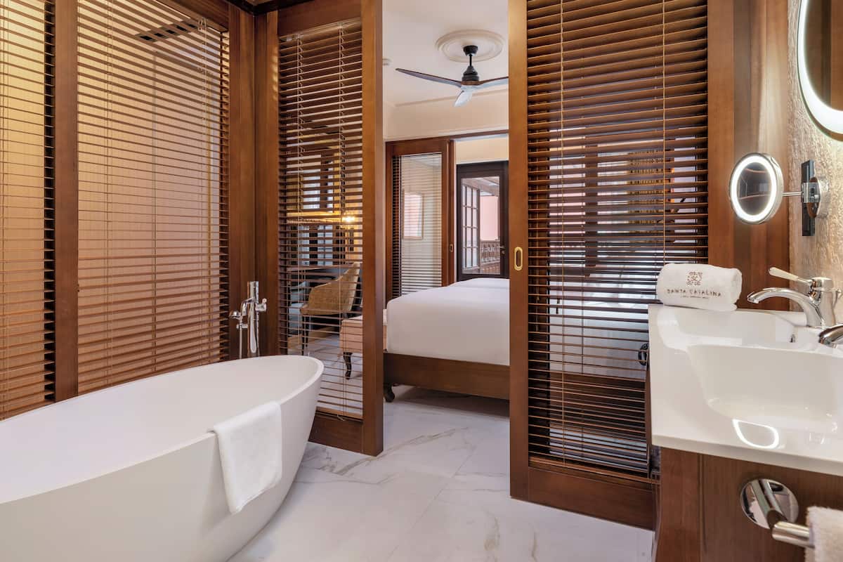 Un baño moderno con bañera, lavamanos y persianas de madera.