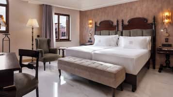 A hotel room with a large bed, a bench, a desk, and a chair.