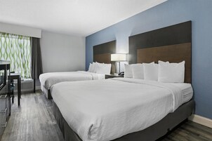 Habitación de hotel con dos camas, un escritorio y una lámpara.