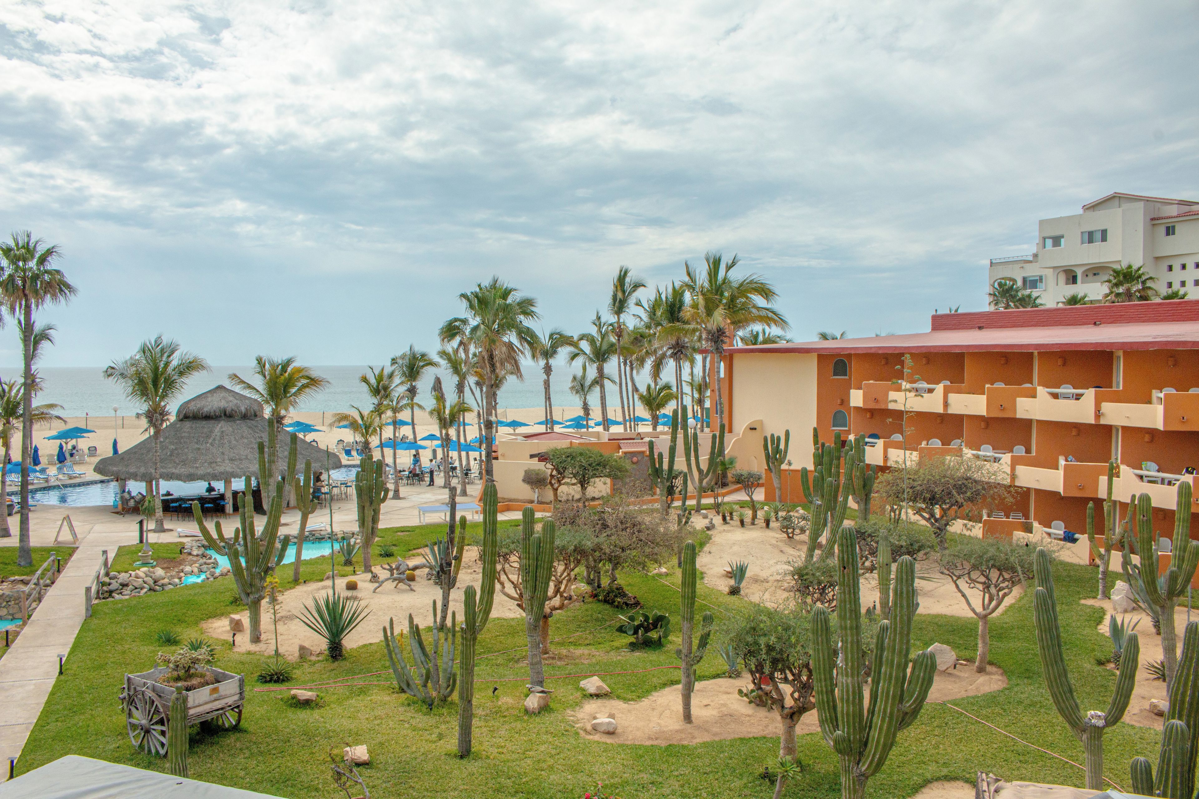 A resort with a pool, palm trees, and a building with balconies.