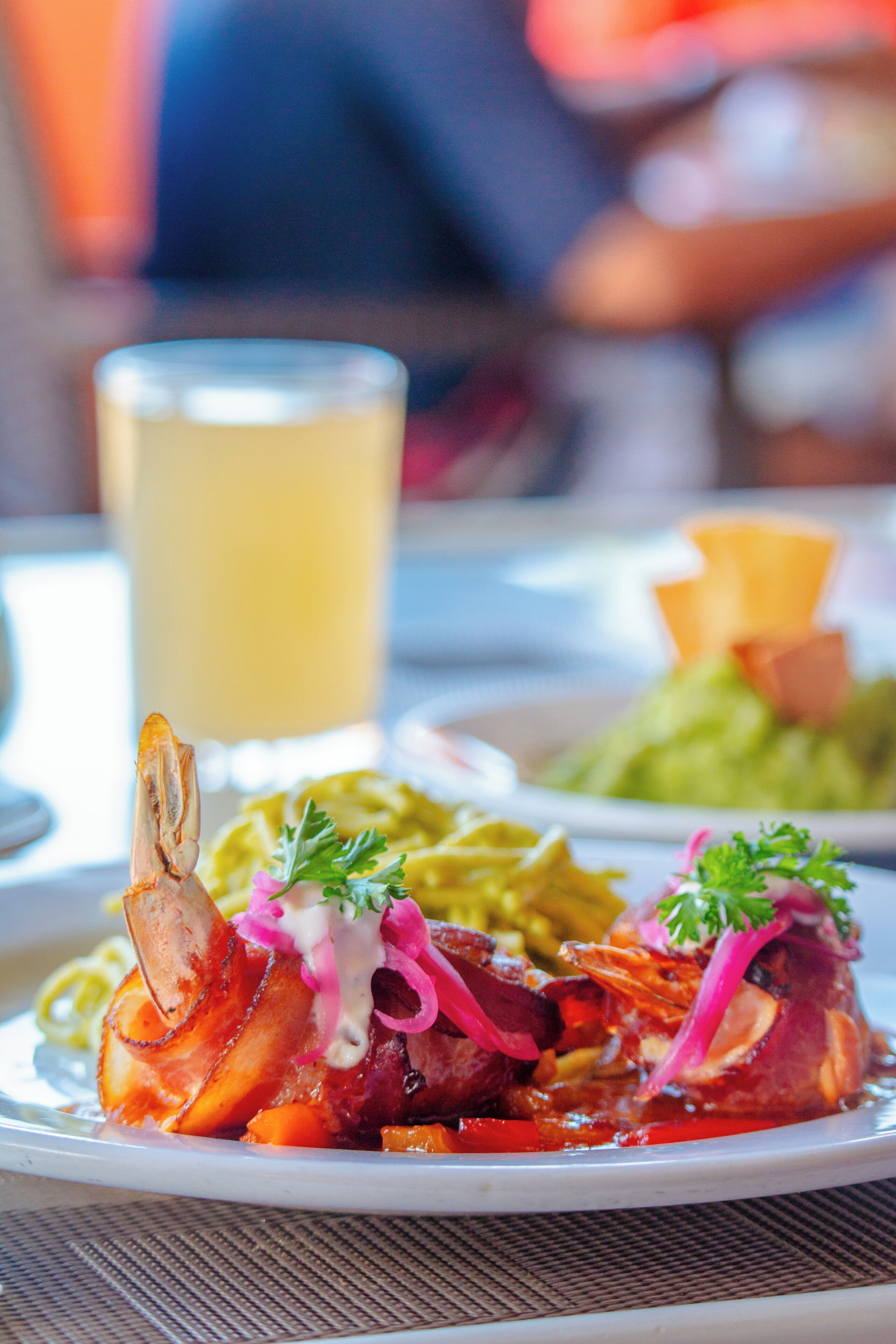 Un plato de comida con camarones, verduras y salsa.