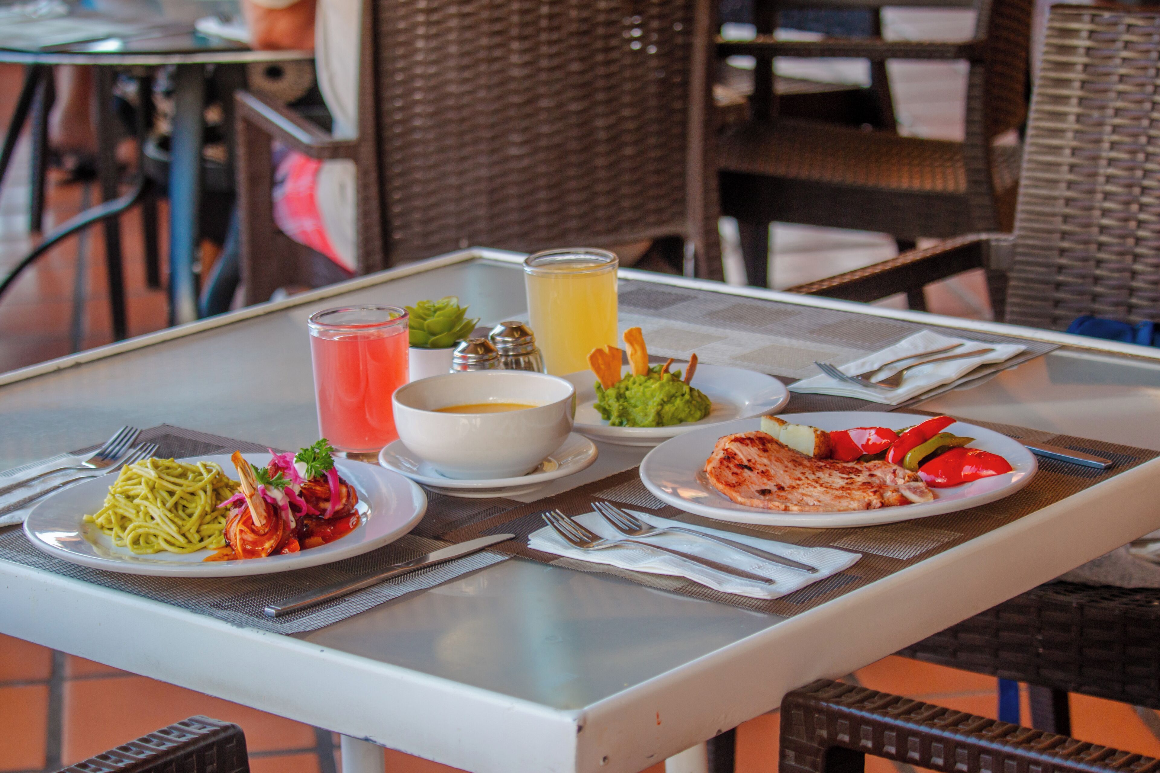 Une table avec des assiettes de nourriture, un verre de jus de fruits et des condiments.
