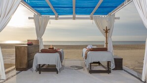 A beachside room with two beds, a wooden chest, and a view of the ocean.