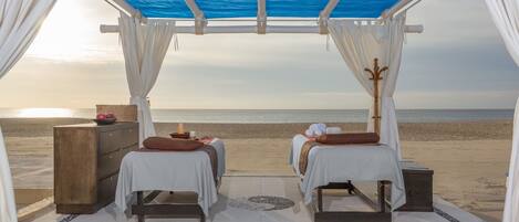 A beachside room with two beds, a wooden chest, and a view of the ocean.