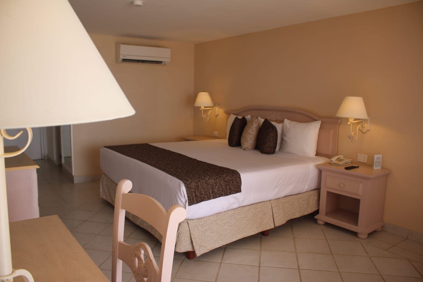 Une chambre d’hôtel avec un lit, des tables de chevet, une chaise et une lampe.
