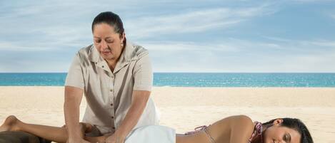 A massage therapy session on a beach with a clear sky.