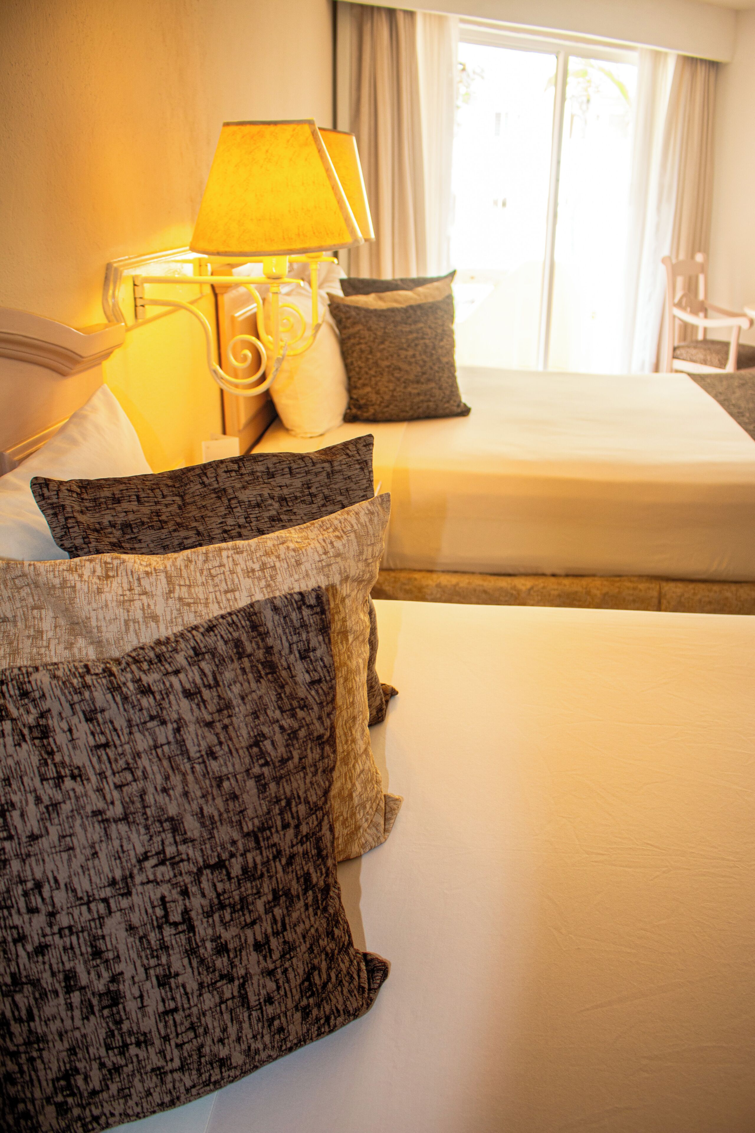 Ein Hotelzimmer mit Bett, Kissen, einer Lampe und einem Sessel.