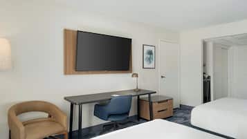 A hotel room with a bed, a desk with a chair, a television, and a door leading to a closet.