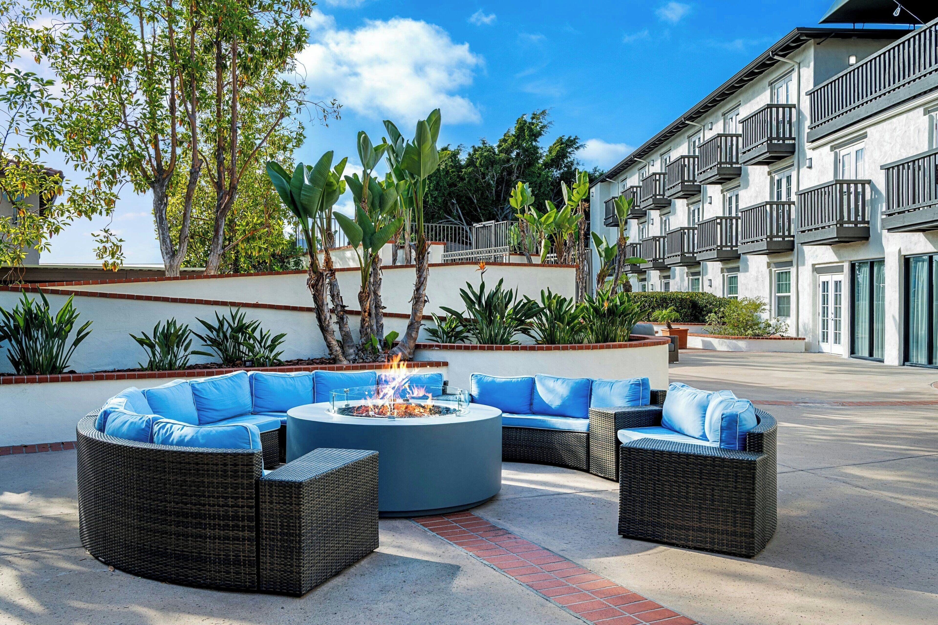 An outdoor seating area with wicker furniture and a central fire feature.