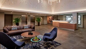 Um hall moderno com um sofá de couro, duas poltronas, uma mesa de centro e uma receção.