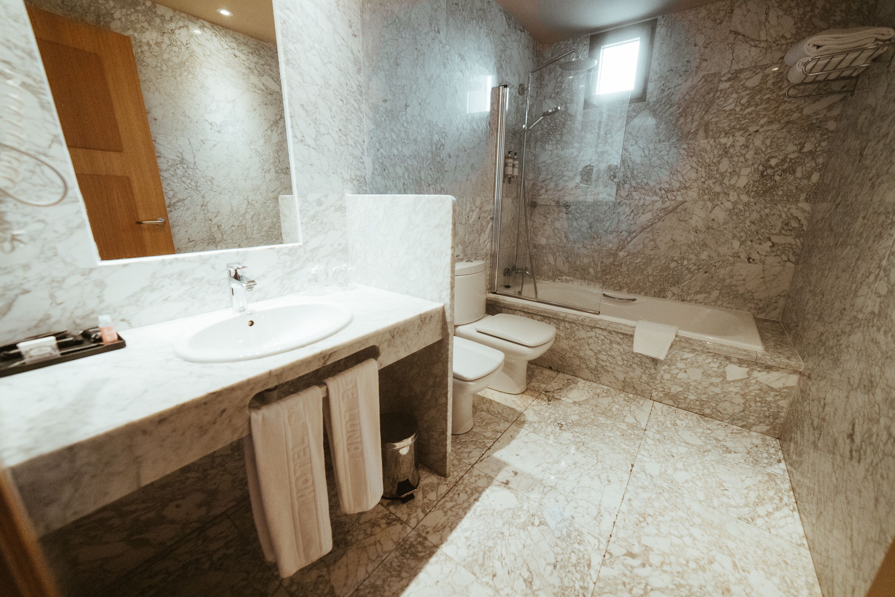 A bathroom with a marble sink, a toilet, and a shower.