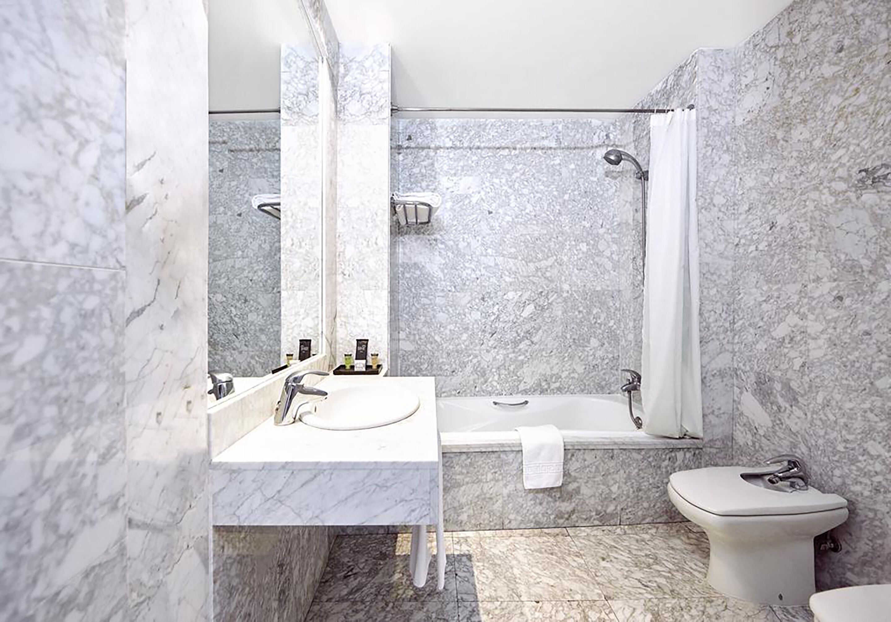 Un baño moderno con lavamanos de mármol, bañera y retrete.