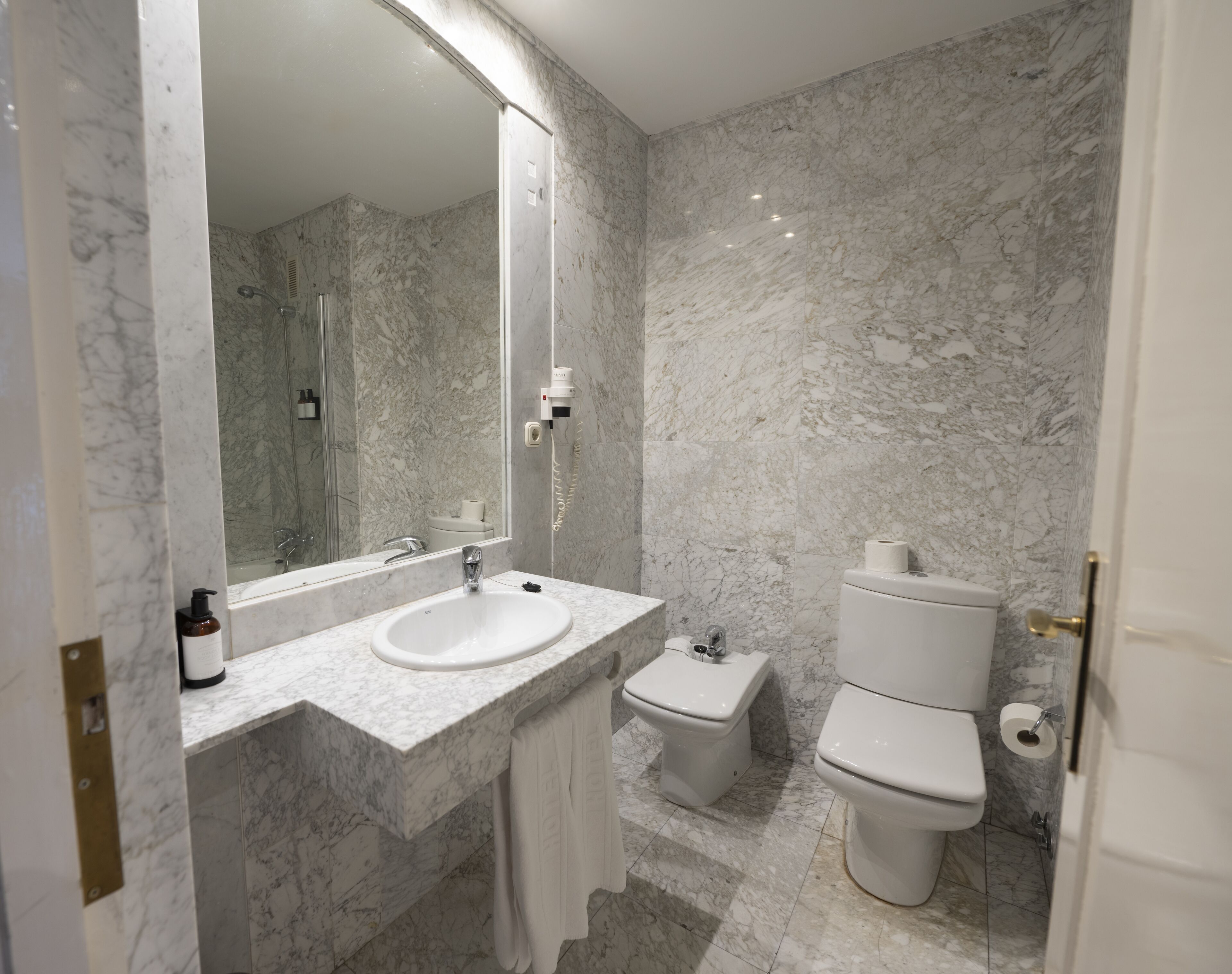 A modern bathroom with a marble sink, a toilet, and a shower.