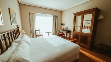 Una habitación de hotel con una cama grande, un escritorio, una silla y un armario.