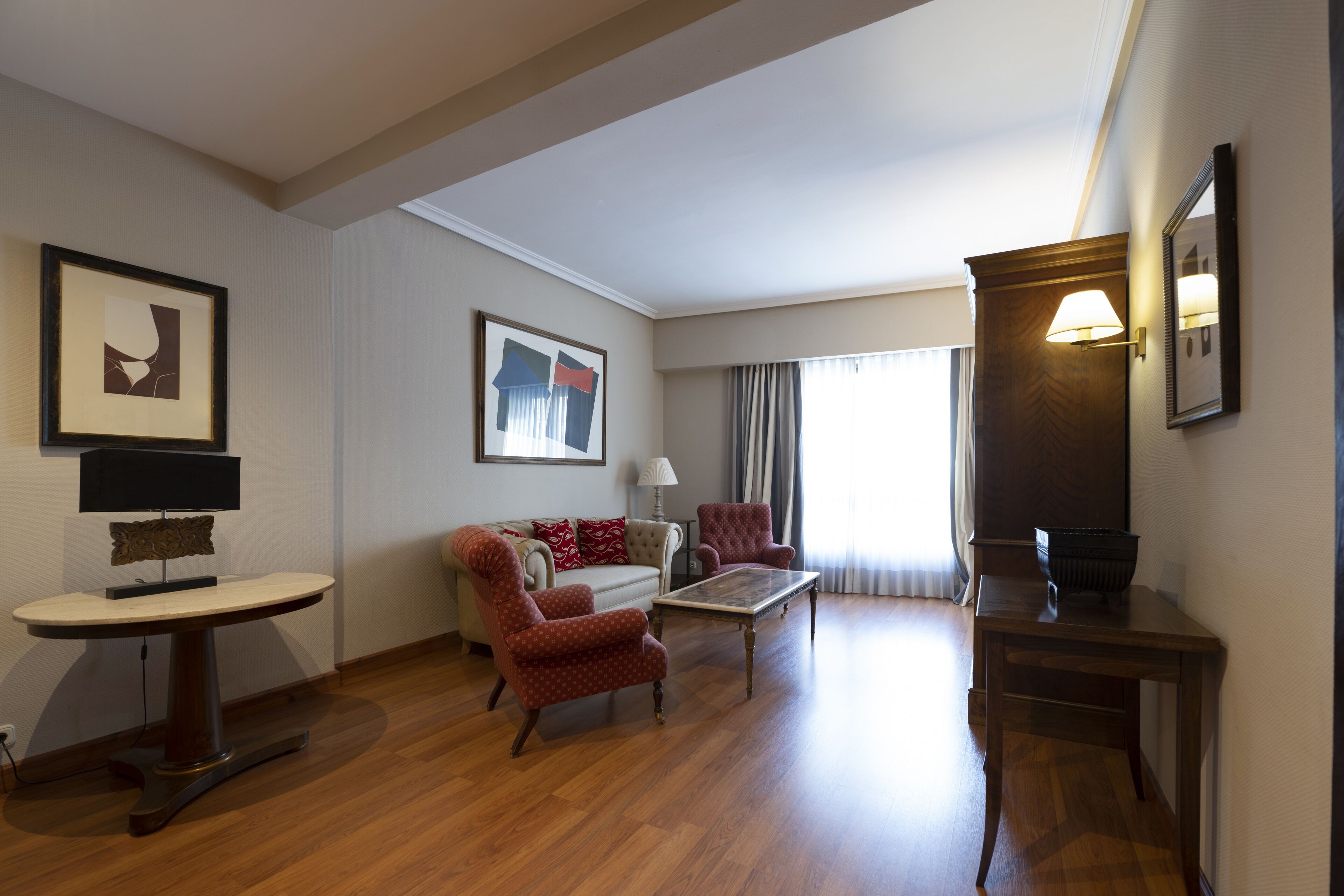 Amplia sala de estar con sofá, sillones, una mesa de centro y un mueble para televisión.
