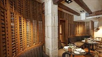 Un comedor con separadores de madera celosía, pilares de piedra y asientos tapizados.