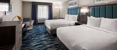 A hotel room with two beds, a desk, a chair, a dresser, and a window with curtains.