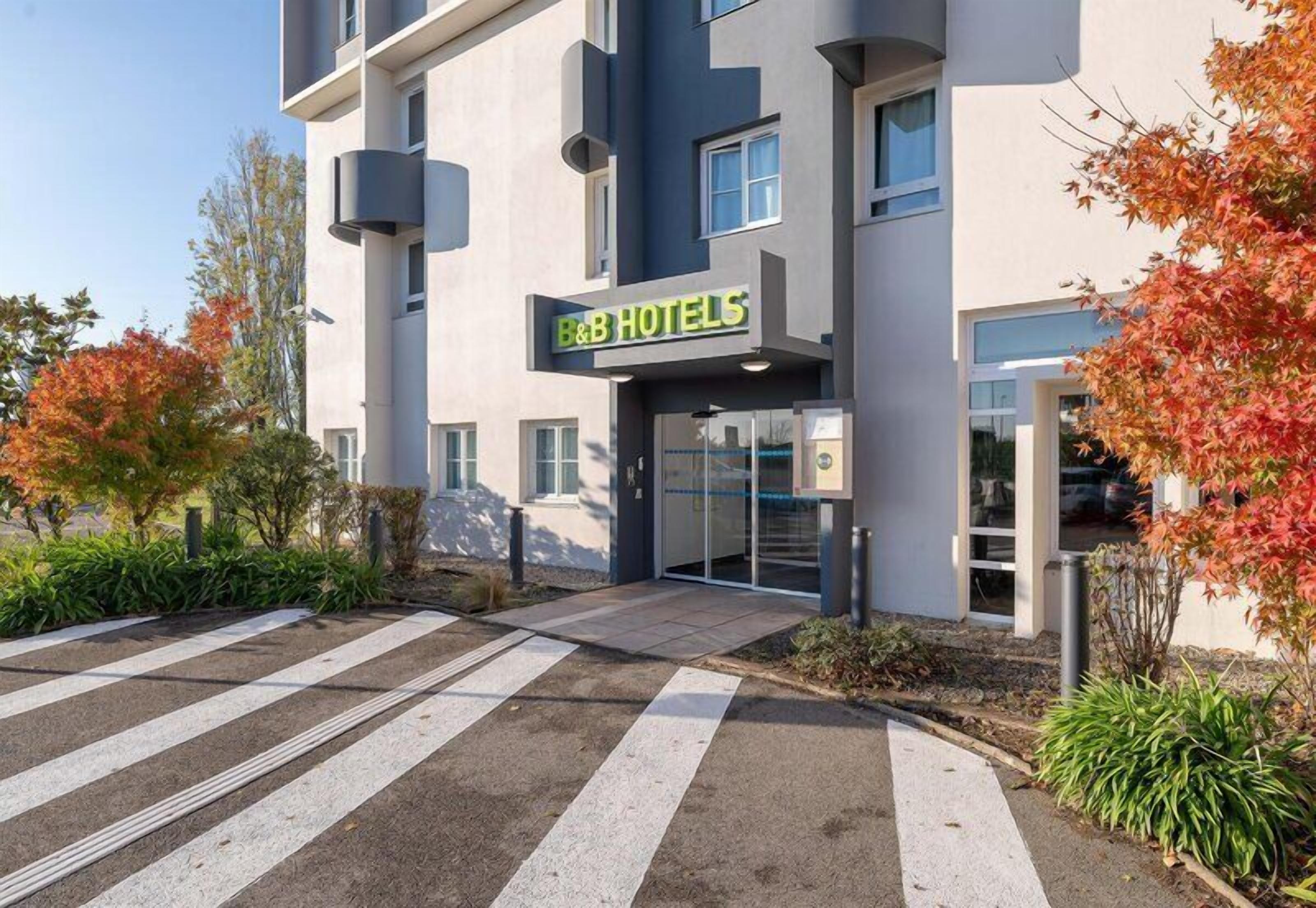 A modern hotel with a flat facade, a prominent entrance, and a crosswalk leading to the entrance.