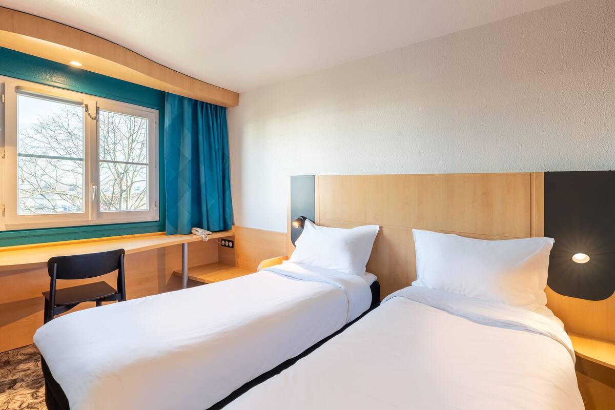 Habitació d'hotel amb dos llits, un escriptori i una cadira.