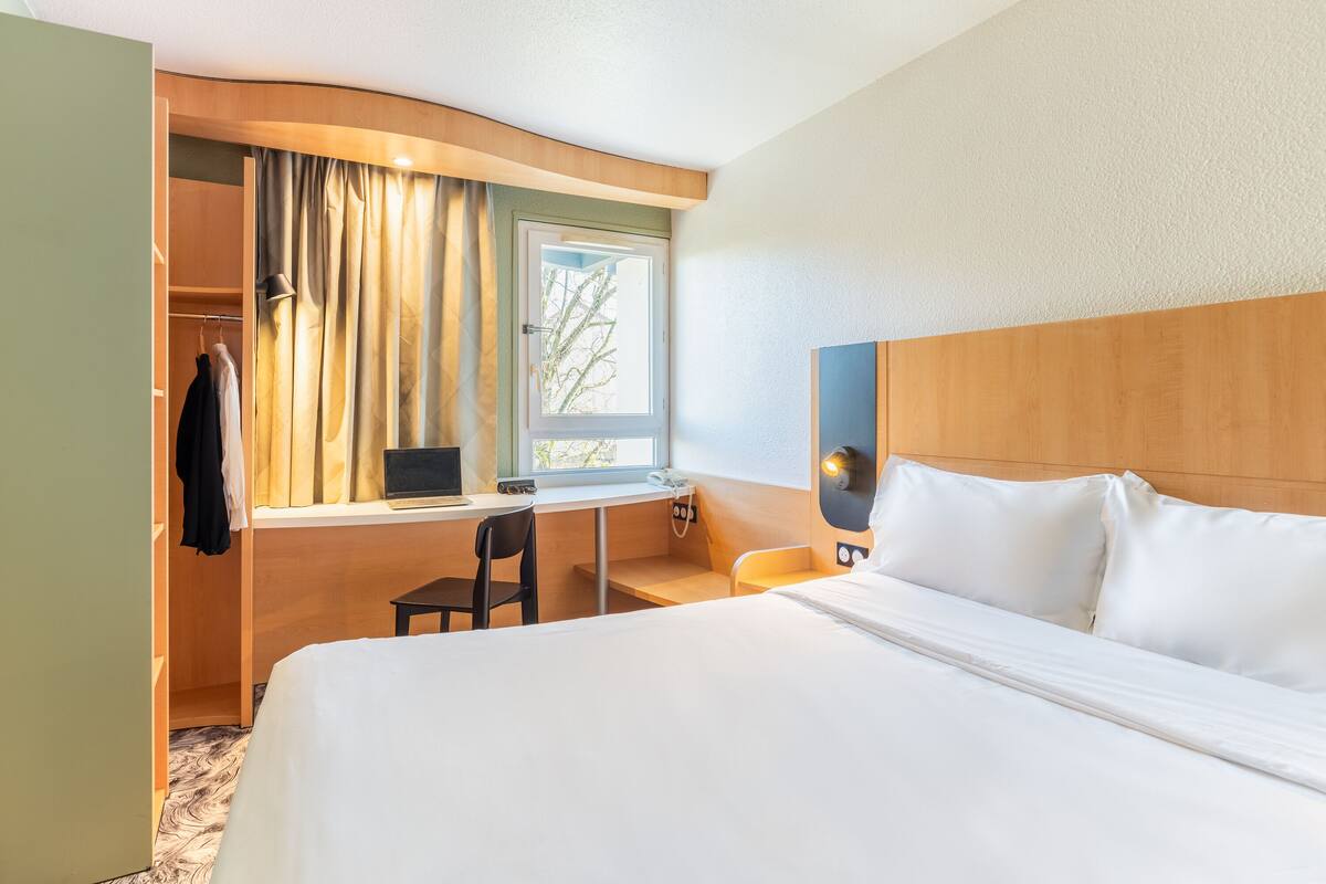Una habitació d'hotel amb llit, escriptori, cadira i armari.