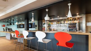 Een moderne bar met een toonbank, barstoelen en diverse flessen.
