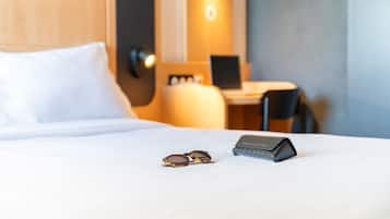 Un lit bien fait, avec une paire de lunettes de soleil et un objet noir posé sur le lit.