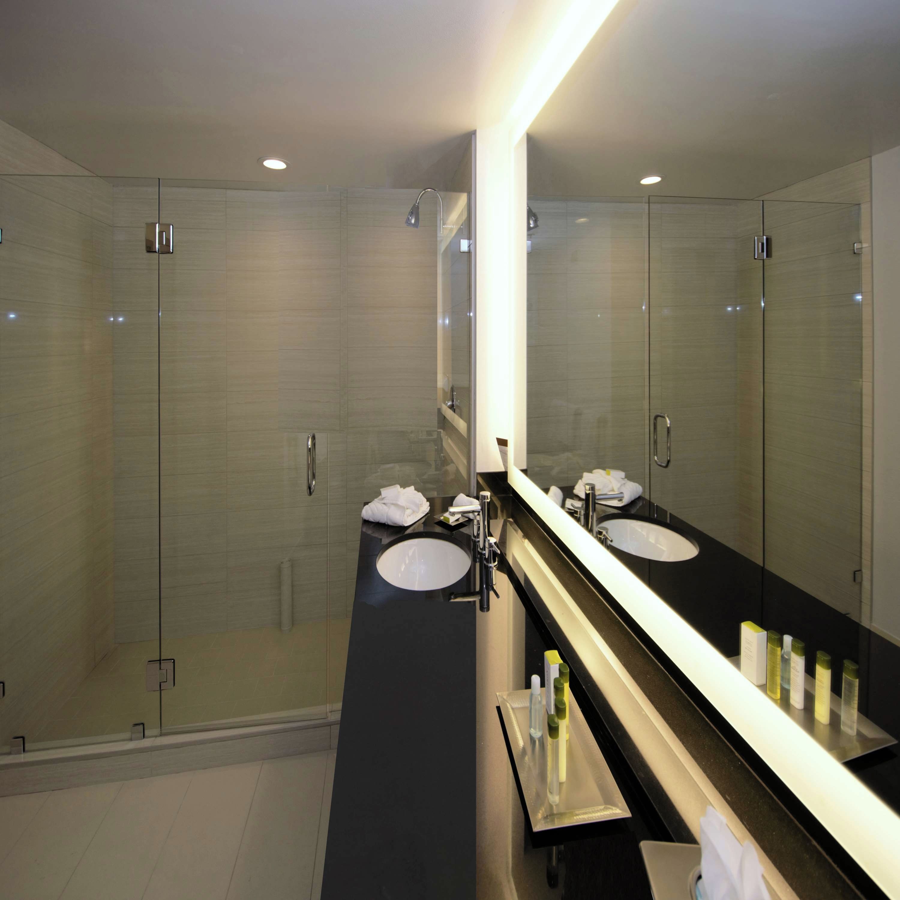 A modern bathroom with a glass-enclosed shower, a black countertop, and a large mirror.