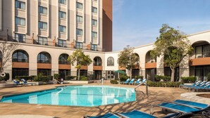 A hotel with a swimming pool, sun loungers, and a clear sky. - Doubletree by Hilton Newark - Fremont (Newark)