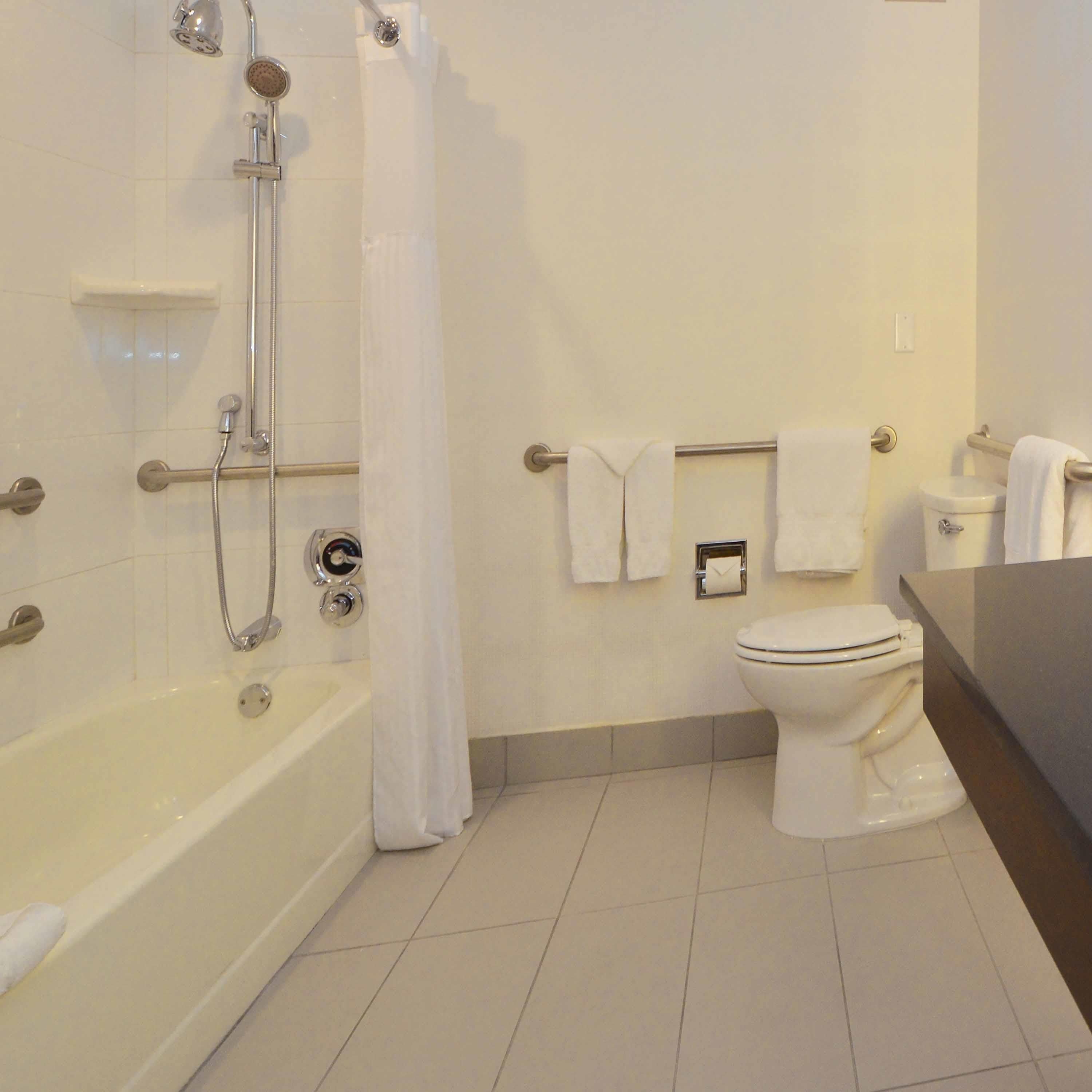 A bathroom with a bathtub, a shower, a toilet, and a towel rack with multiple towels.