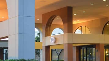 A hotel entrance with a modern design, featuring large arches and a prominent logo above the doors.