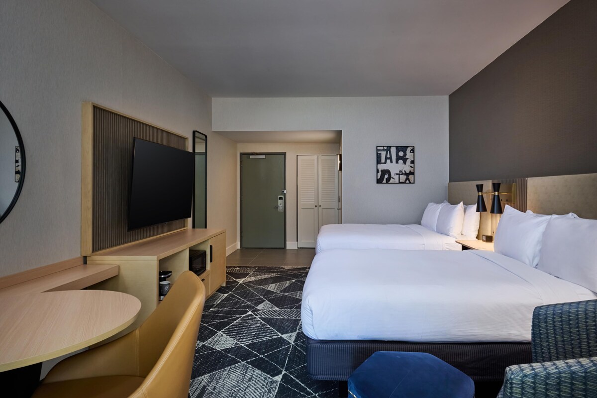 A hotel room with a large bed, a TV, a desk, and a seating area.