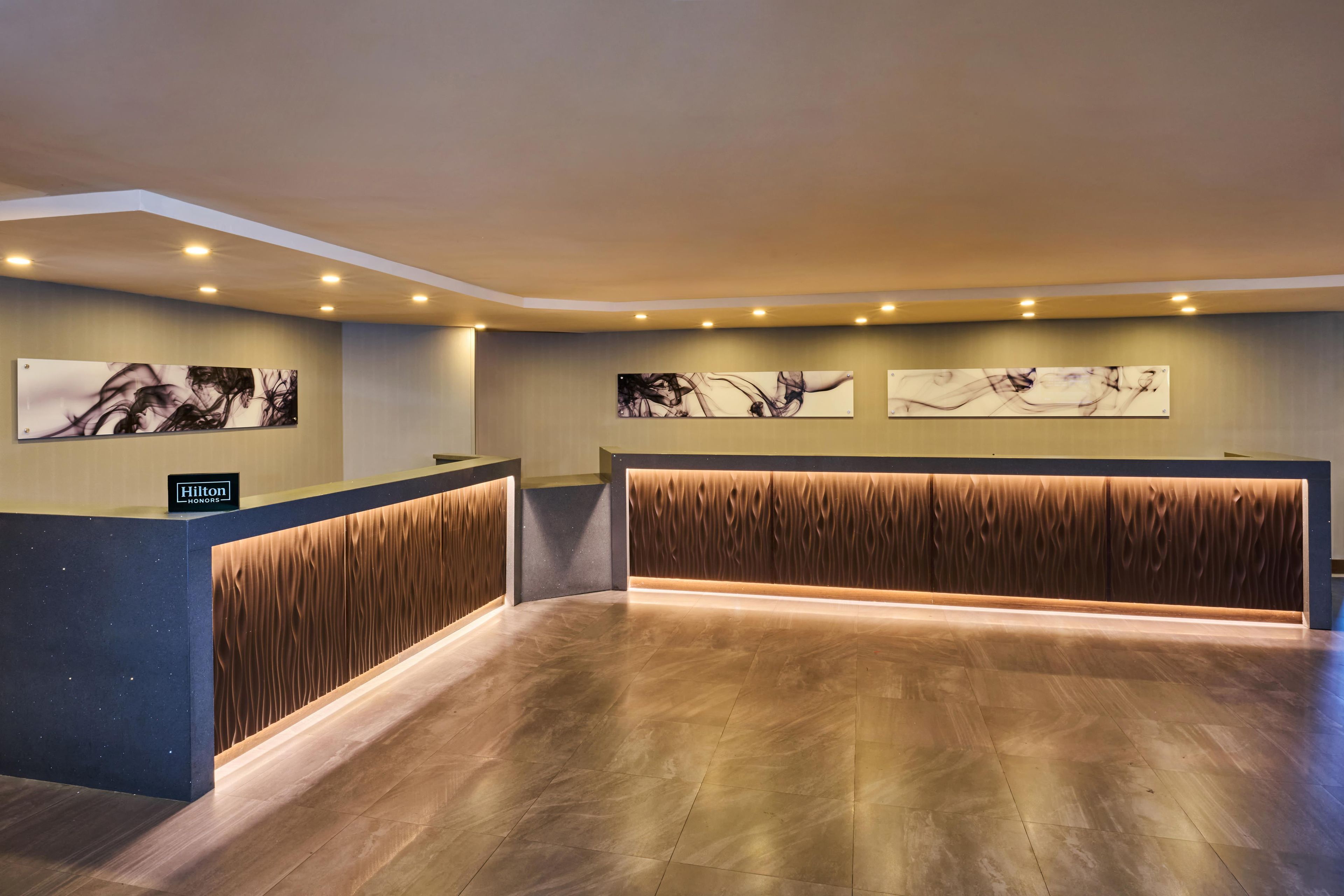 Et hotellets receptionområde med moderne design, inklusive en træreception, loungeområde og kunst på væggene.