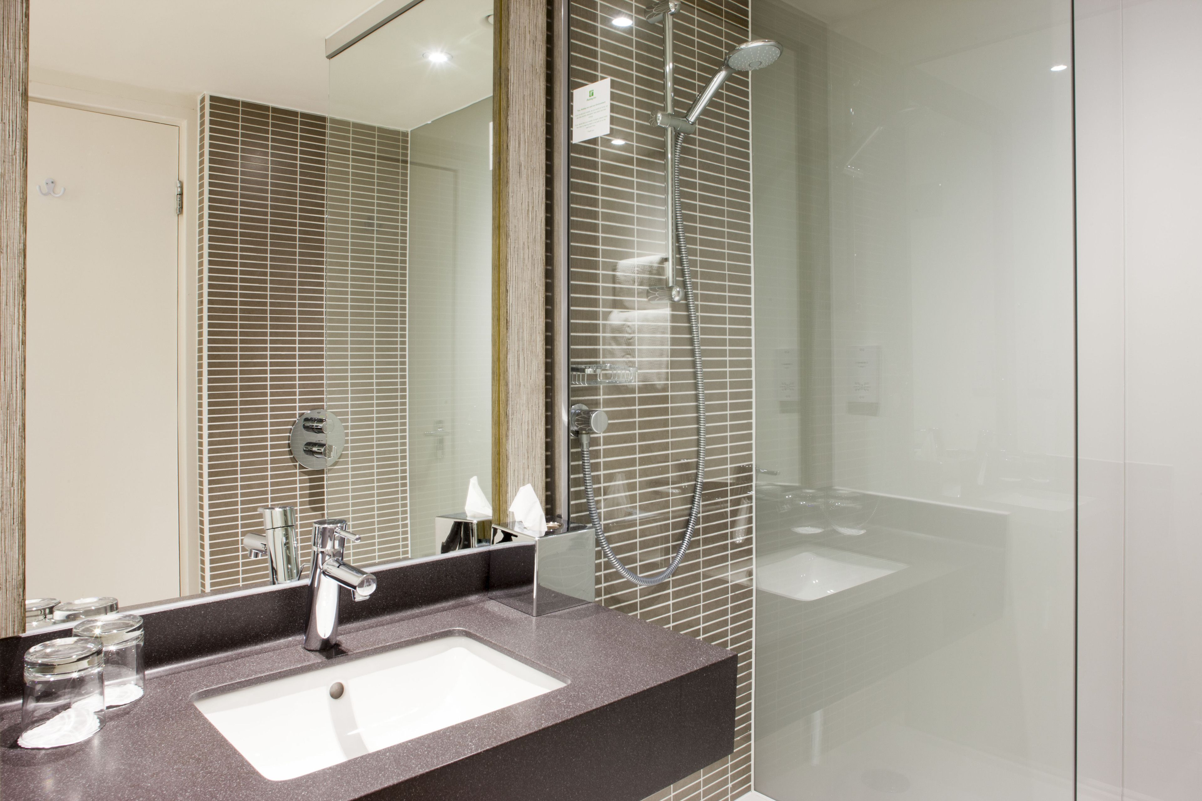 Un baño moderno con un espejo grande, un lavamanos y una ducha.