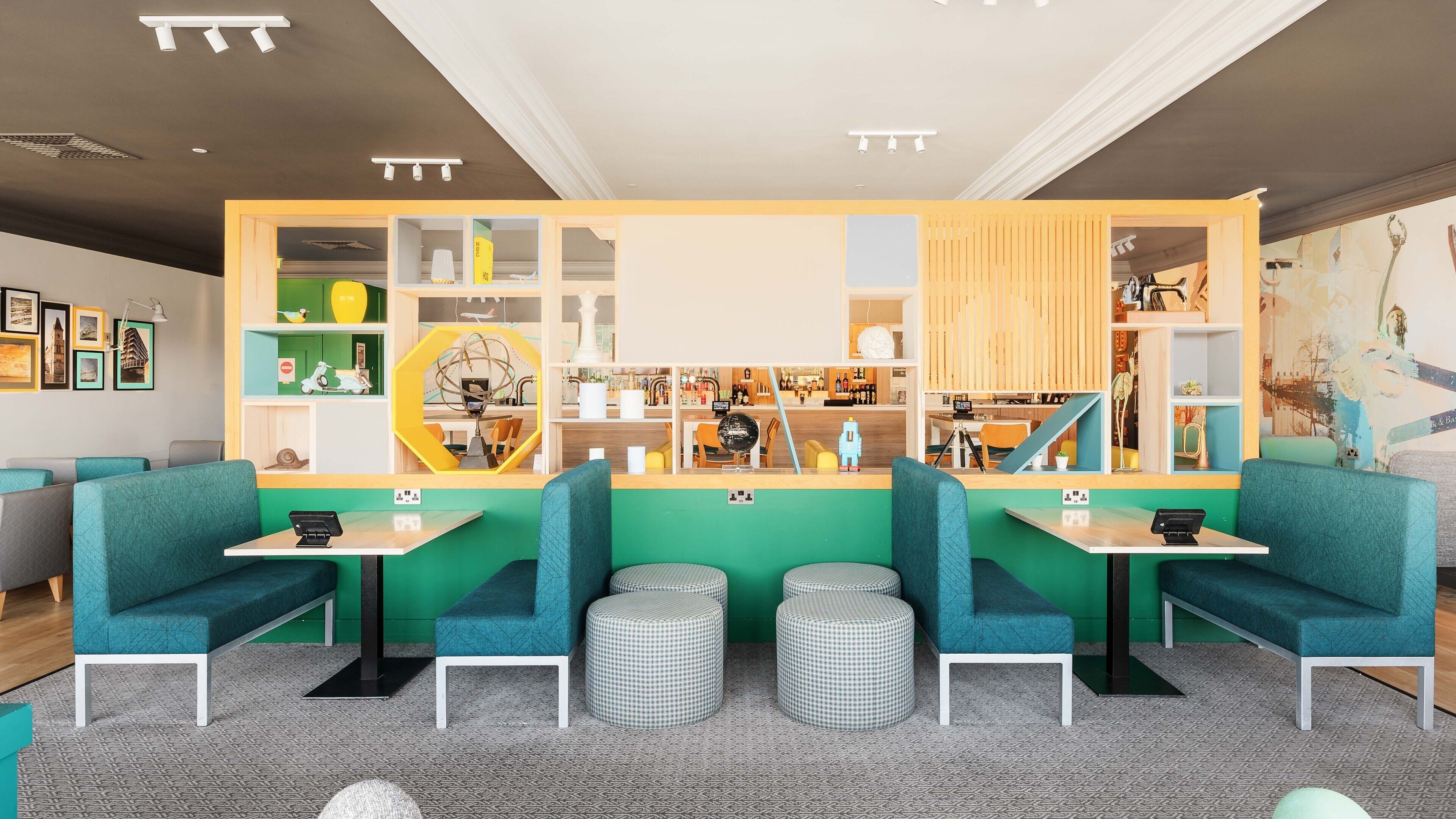 Eine moderne Bar mit grünen Sitzgelegenheiten, einer zentralen Theke und einer gut sortierten Bar.