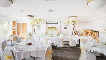 A banquet hall with round tables, white tablecloths, and chairs with yellow sashes.