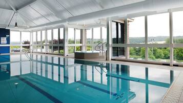 An indoor swimming pool with clear glass walls, a view of the outdoors, and a no diving sign.