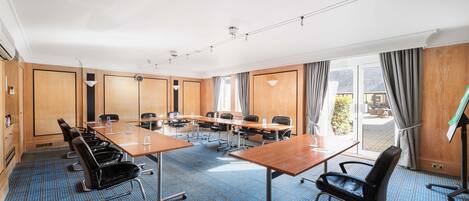Un salón de conferencias con una larga mesa, sillas y vistas al exterior.