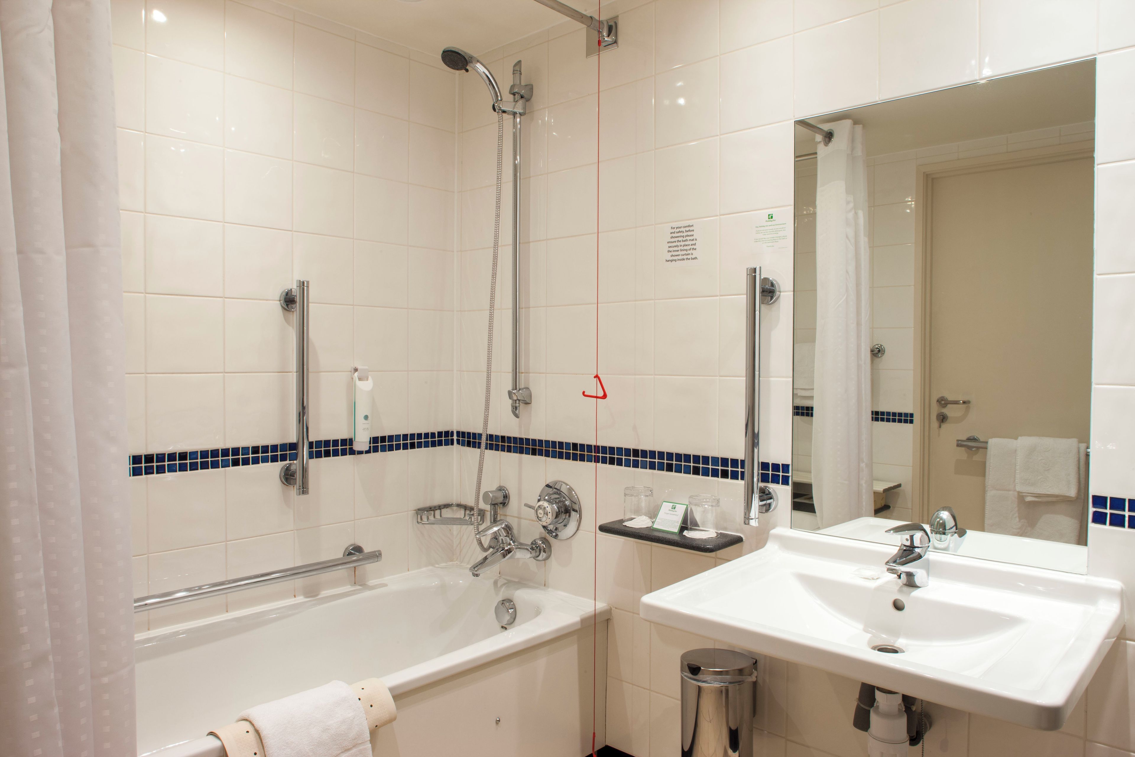 A bathroom with a bathtub, a shower, a sink, and a mirror.