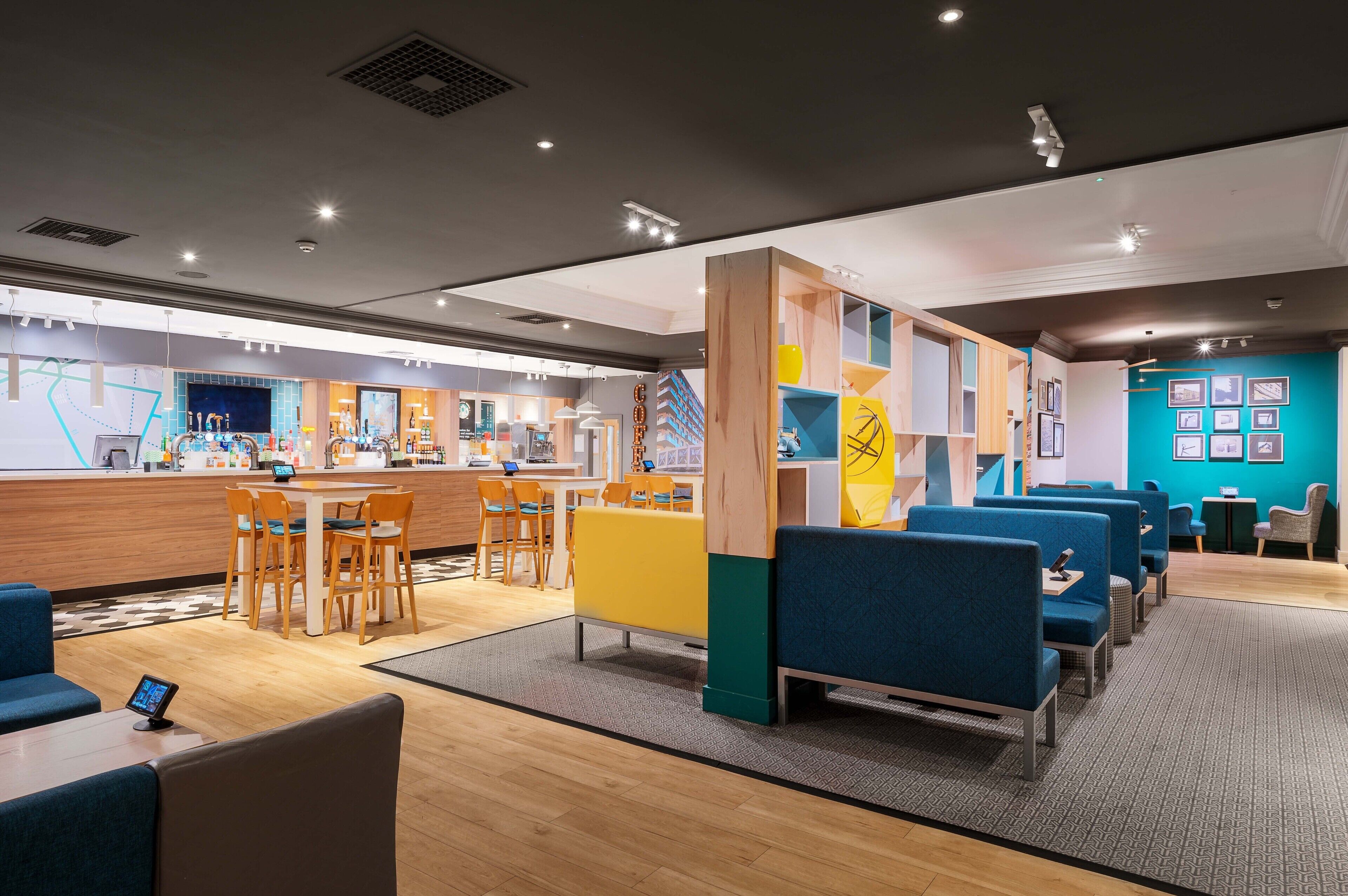A modern hotel lobby with a reception desk, seating area, and a children's play zone.