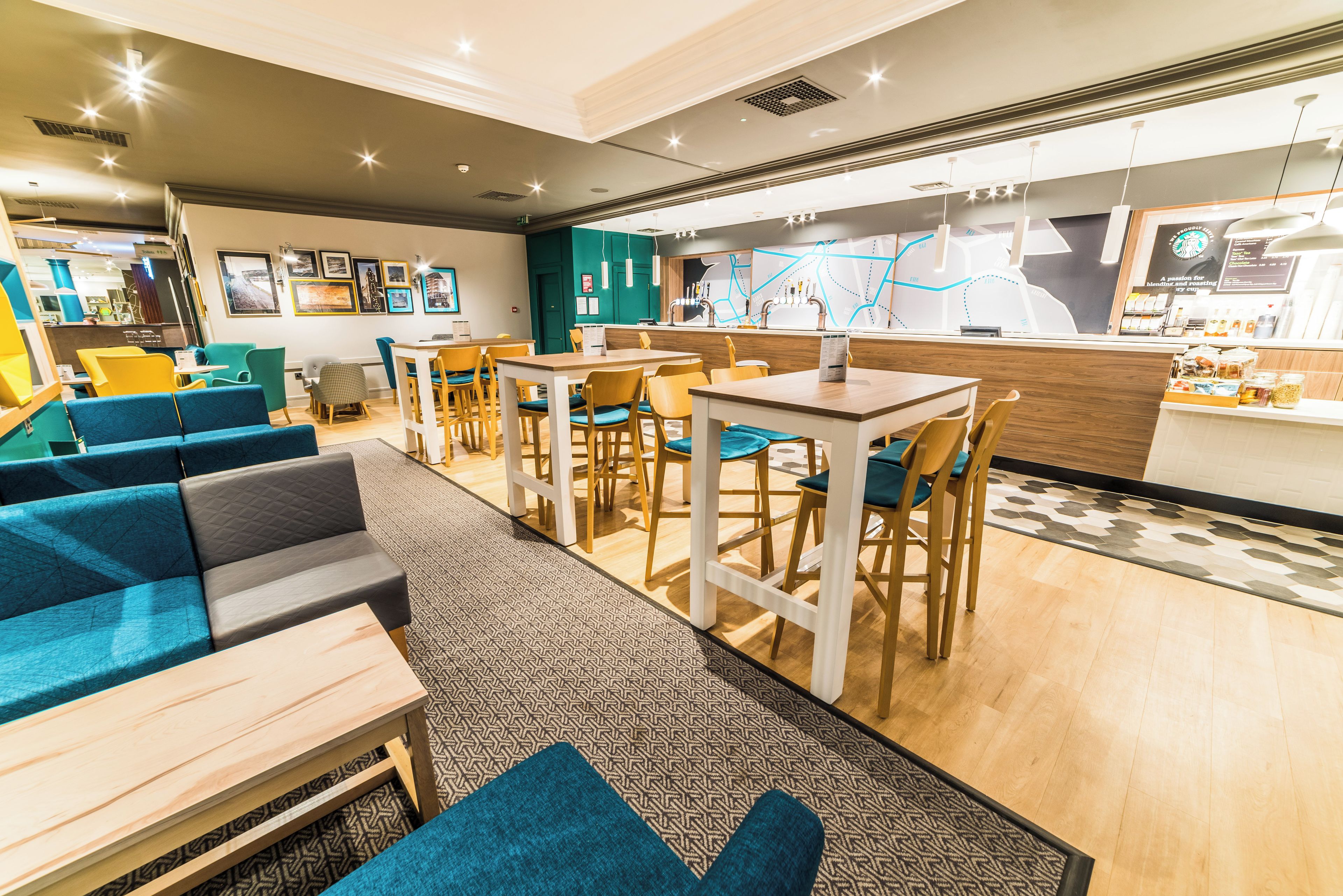 A modern cafe with seating arrangements, a counter with a menu, and a wall with framed pictures.