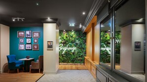 A modern lobby with a teal wall, framed pictures, a neon sign, and a green wall with plants. - Holiday Inn Brighouse by IHG (Brighouse)