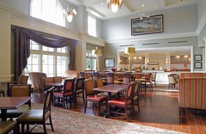Enjoy meals in this dining area with tables and chairs, a high ceiling, and a large window.