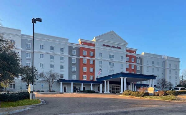 Welcome to Hampton Inn & Suites, a hotel with a grand entrance featuring a blue canopy and white columns.