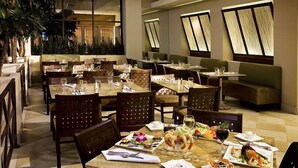 A restaurant with multiple tables and chairs, some with plates of food and drinks.
