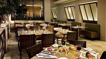 A restaurant with multiple tables and chairs, some with plates of food and drinks.