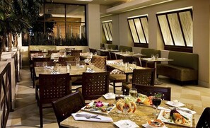A restaurant with multiple tables and chairs, some with plates of food and drinks.